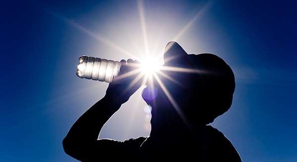 Man drinking water in front of a hot sun